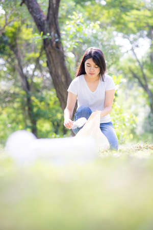 Woman hand picking up garbage plastic for cleaning at parkの写真素材