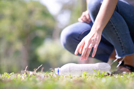 Woman hand picking up garbage plastic for cleaning at parkの写真素材