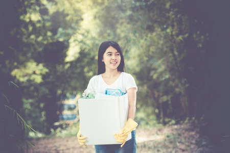 Woman hand picking up garbage plastic and Glass bottles for cleaning at parkの写真素材