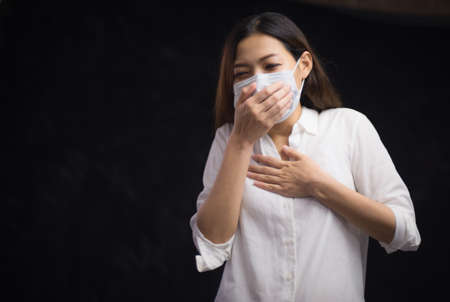 Corona virus, or Covid-19, is spreading all over the world. Portrait of an Asian woman wearing a black oil mask, anti-virus, or anti-Covid-19. Feeling stressedの写真素材