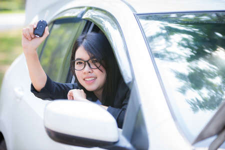 Asian businesswoman is stressed and looks at the broken car's room, calling a repairman.の写真素材
