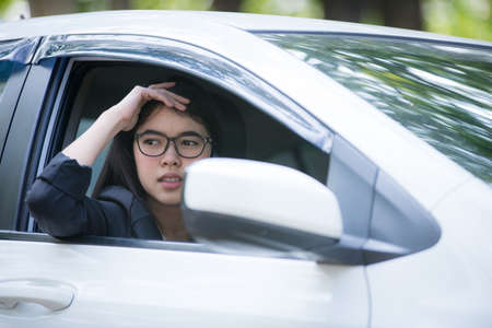 Asian business woman sad waiting for help by a broken car. Use a mobile phone to call the mechanic.の写真素材
