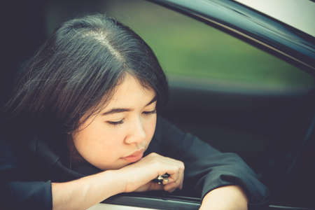 Asian business woman sad waiting for help by a broken car. Use a mobile phone to call the mechanic.の写真素材