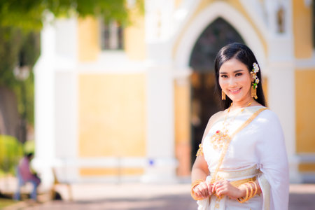 Beautiful girl in White Thai dress with red lotus flowers.Thai girl in retro Thai dress,Beautiful Thai girl in traditional dress costumeの写真素材