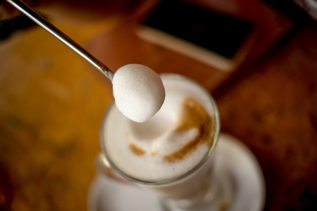 Coffee cappuccino with fluffy white milk on top. Placed on a wooden table ready to serve you.の写真素材