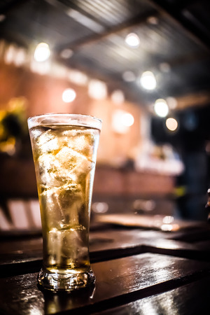 Blurred Background Cold lager Beer glass on the bar counter in dark pub.の写真素材