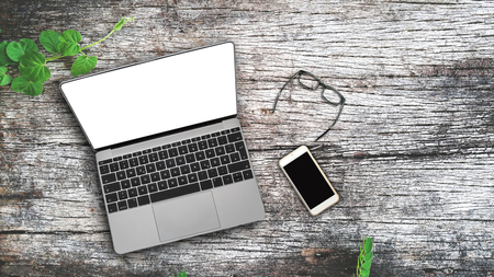 Desktop Mix of office supplies and gadgets . desk with laptop , Smart Phone, glasses , Watch , notebook , tablet, On a wood table.の写真素材