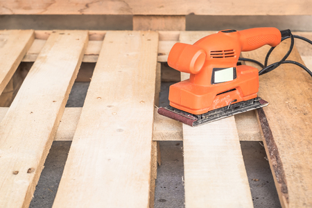 Wood sanding machines , Carpenter working with electrical sander on pine floor or table surfaceの写真素材