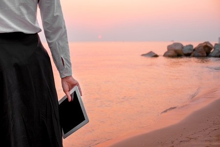 young business woman relaxing working Using tablet and Toe Foot touches the sea on the beach At the time of sunset . happy at work Concept .の写真素材