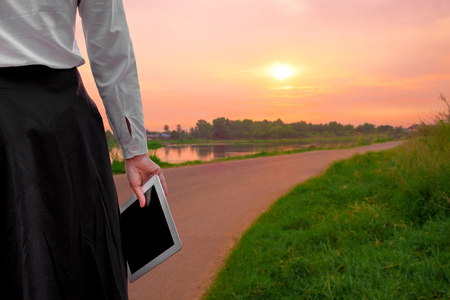 young business woman relaxing working Using tablet on the Country Roads At the time of sunset . happy at work Concept .の写真素材