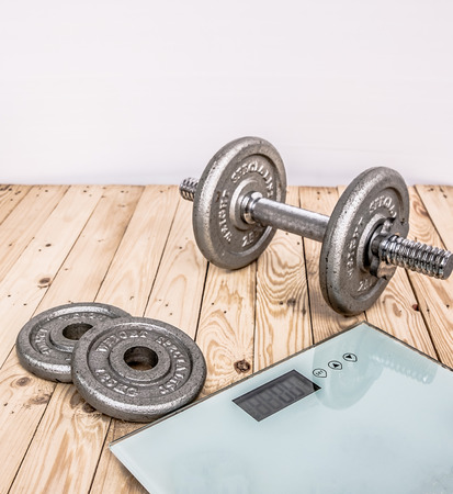 Dumbbells , weight plates and bottle of water on wooden background for bodybuilder. Concept for sport player or workout. gym of accessories for fitnessの写真素材
