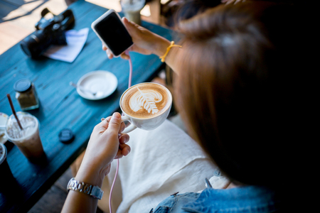 Happy business young woman taking selfie with Smart Phone Enjoyment with Cappuccino , Latte art coffee and relax In her holiday .の写真素材
