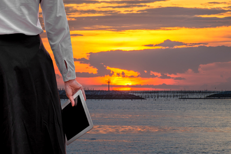 young business woman relaxing working Using tablet and Toe Foot touches the sea on the beach At the time of sunset . happy at work Concept .の写真素材
