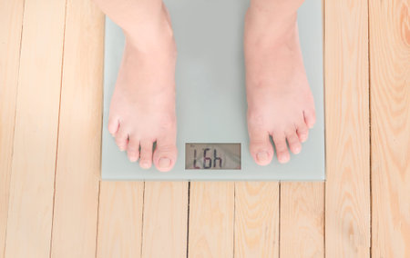 Low Section Of Overweight Person Standing On Weighing Scale