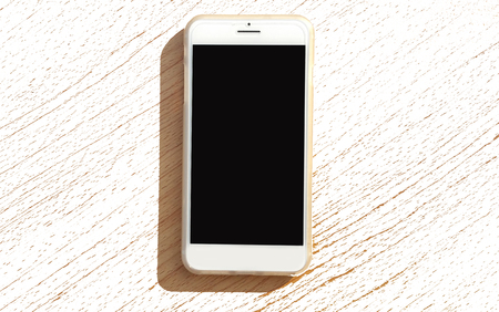 Modern mobile smart phone with black screen for mockup On a wooden table .の写真素材
