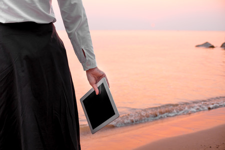 young business woman relaxing working Using tablet and Toe Foot touches the sea on the beach At the time of sunset . happy at work Concept .の写真素材