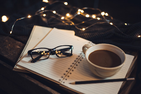 Glasses and coffee are placed on the notebook.の写真素材