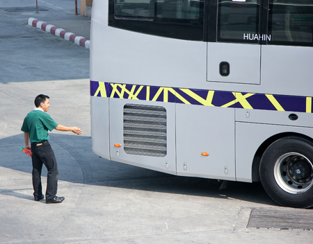 CHIANG MAI, THAILAND - FEBRUARY 28 2015: Man give signs for bus Reverse out of terminal. Bus of Greenbus Company. Photo at New Chiangmai bus station, thailand.のeditorial素材