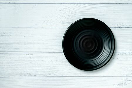 An empty plate resting on a white wooden floor.の写真素材