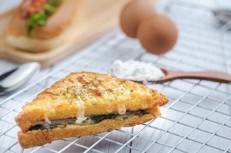 croque monsieur with slices of boiled ham, placed on a wooden plate with cooking tools.の写真素材