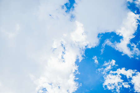 Bright sky in the daytime with white clouds and sunlight shining down.の写真素材