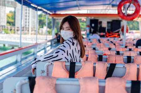 Thai women wearing a mask to prevent the outbreak of covid-19, A new normal tourism protection from the epidemic in 2020, Women sitting on a passenger boat floating on the sea, Concept of covid-19 preの写真素材