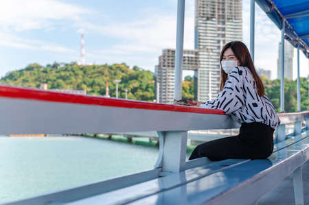 Thai women wearing a mask to prevent the outbreak of covid-19, A new normal tourism protection from the epidemic in 2020, Women sitting on a passenger boat floating on the sea, Concept of covid-19 preの写真素材
