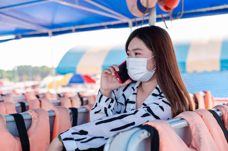 Thai women wearing a mask to prevent the outbreak of covid-19, A new normal tourism protection from the epidemic in 2020, Women sitting on a passenger boat floating on the sea, Concept of covid-19 preの写真素材