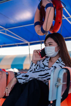 Thai women wearing a mask to prevent the outbreak of covid-19, A new normal tourism protection from the epidemic in 2020, Women sitting on a passenger boat floating on the sea, Concept of covid-19 preの写真素材