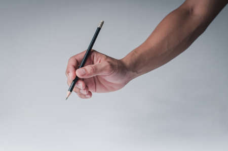 Man's hand holding a black pen and pencil showing gesture writing on a white background, educational concept, office work concept.の写真素材