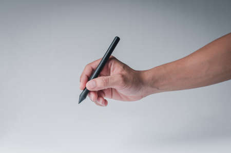 Man's hand holding a black pen and pencil showing gesture writing on a white background, educational concept, office work concept.の写真素材