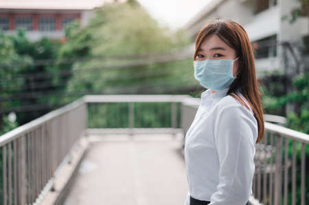 Asian woman wearing a mask Standing at the overpass waiting for a rail car in the subway. Unemployed young women holding a job application. Covid 19 Concept, Development concept, Business concept.の写真素材