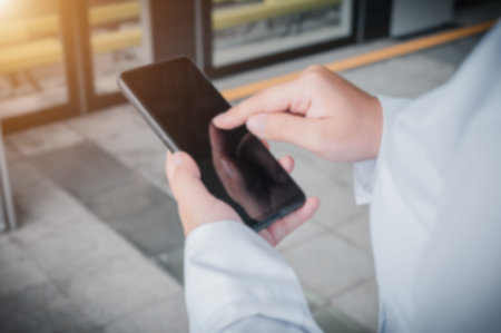 Woman holding a smartphone with a blank screen while waiting for the train. Use the image blur...