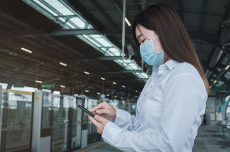 A businesswoman is standing using a mobile phone while waiting for the subway, With stock graphics...