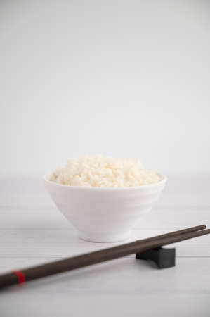 Thai steamed rice in a bowl with a spoon and black chopsticks placed on the side. On a white backdropの写真素材