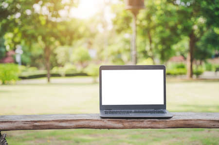 A silver laptop with a blank screen. Placed on an outdoor wooden table for a park tree backdrop.の写真素材