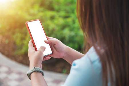 woman using a smartphone in a park, a blank smartphone screen, perspective taken from behind a person.の写真素材