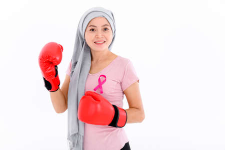 Asian women put a pink ribbon on their tops. And wearing boxing gloves on a colored background Breast cancer concept, cancer prevention concept.の写真素材