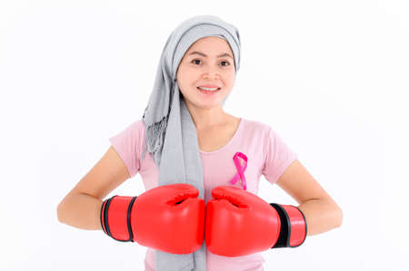 Asian women put a pink ribbon on their tops. And wearing boxing gloves on a colored background Breast cancer concept, cancer prevention concept.の写真素材