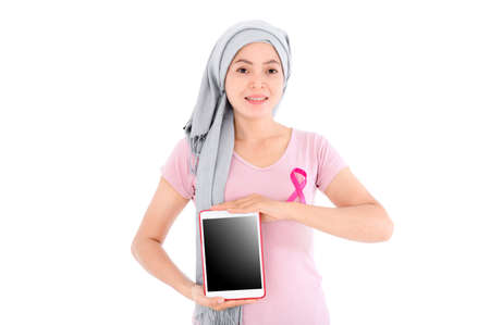 Asian women wear pink ribbons to their tops. Is using a red tablet on a white background. Breast cancer concept, cancer prevention concept. Clipping path.の写真素材