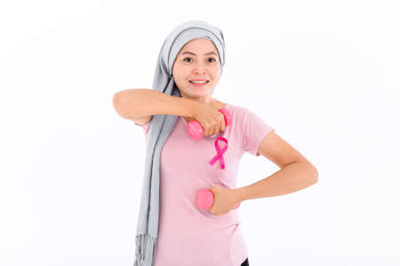 Asian women muslim religious women in hijab attach a pink ribbon to their tops. Doing exercise by lifting pink dumbbells.  breast cancer concept, cancer prevention concept. Acne and dark spots.の写真素材