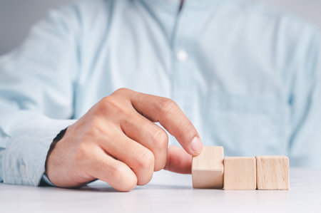 Businessman wearing a blue shirt, arranging the empty wooden blocks with his hands. Which is placed on a white wooden table. Business strategy and action plan. Copy space.の写真素材