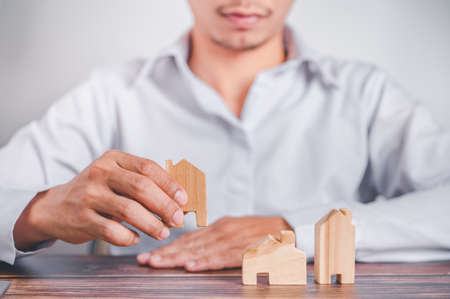 Real estate agent holds a wood house to exchange with his client after signing a home purchase contract, idea for real estate, moving or renting a property.の写真素材