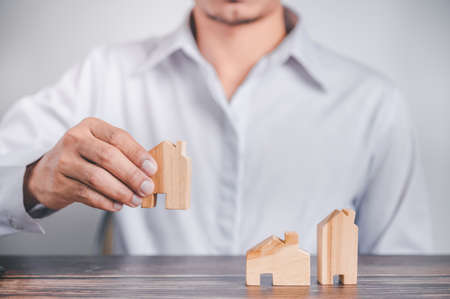 Real estate agent holds a wood house to exchange with his client after signing a home purchase contract, idea for real estate, moving or renting a property.の写真素材