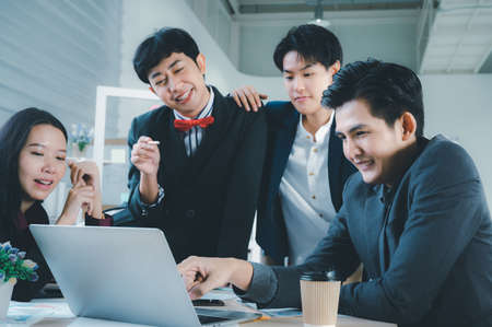 Group of young business people sit at their desks with smiling colleagues together in the office.  Meeting business people  planning concept, laptop meeting ideas. Concentrate on work. LGBT teamwork.の写真素材