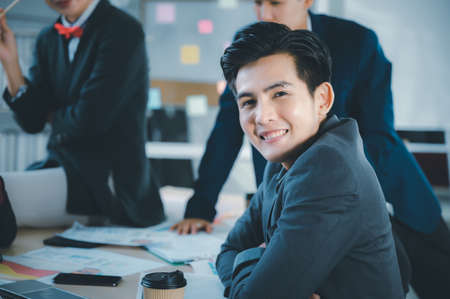 Group of young business people sit at their desks with smiling colleagues together in the office.  Meeting business people  planning concept, laptop meeting ideas. Concentrate on work. LGBT teamwork.の写真素材