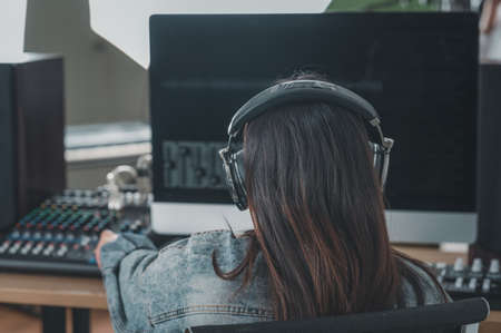 Asian female singer with a passion for music and microphone. While playing her guitar in a professional studio. Music concept, sound recording concept.の写真素材