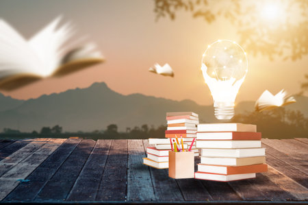 Piles of books and pens are placed on the ground with a background of the morning mountain view. The...