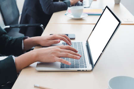 Businessman working at a home office uses a close-up keyboard, a man sitting on a wooden table and using a contemporary laptop by the window. Concept of close-up of a hand printed on a laptop.の写真素材