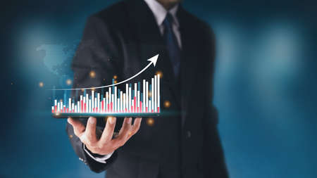 Businessman hand show Stock chart showing rising stock sign with graph indicator. Interest rate financial and mortgage rates concept. Double Exposure Image. Blue technology background high tech.の写真素材